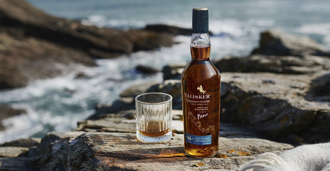 Bottle of Talisker 44-year-old whisky and a glass by the sea