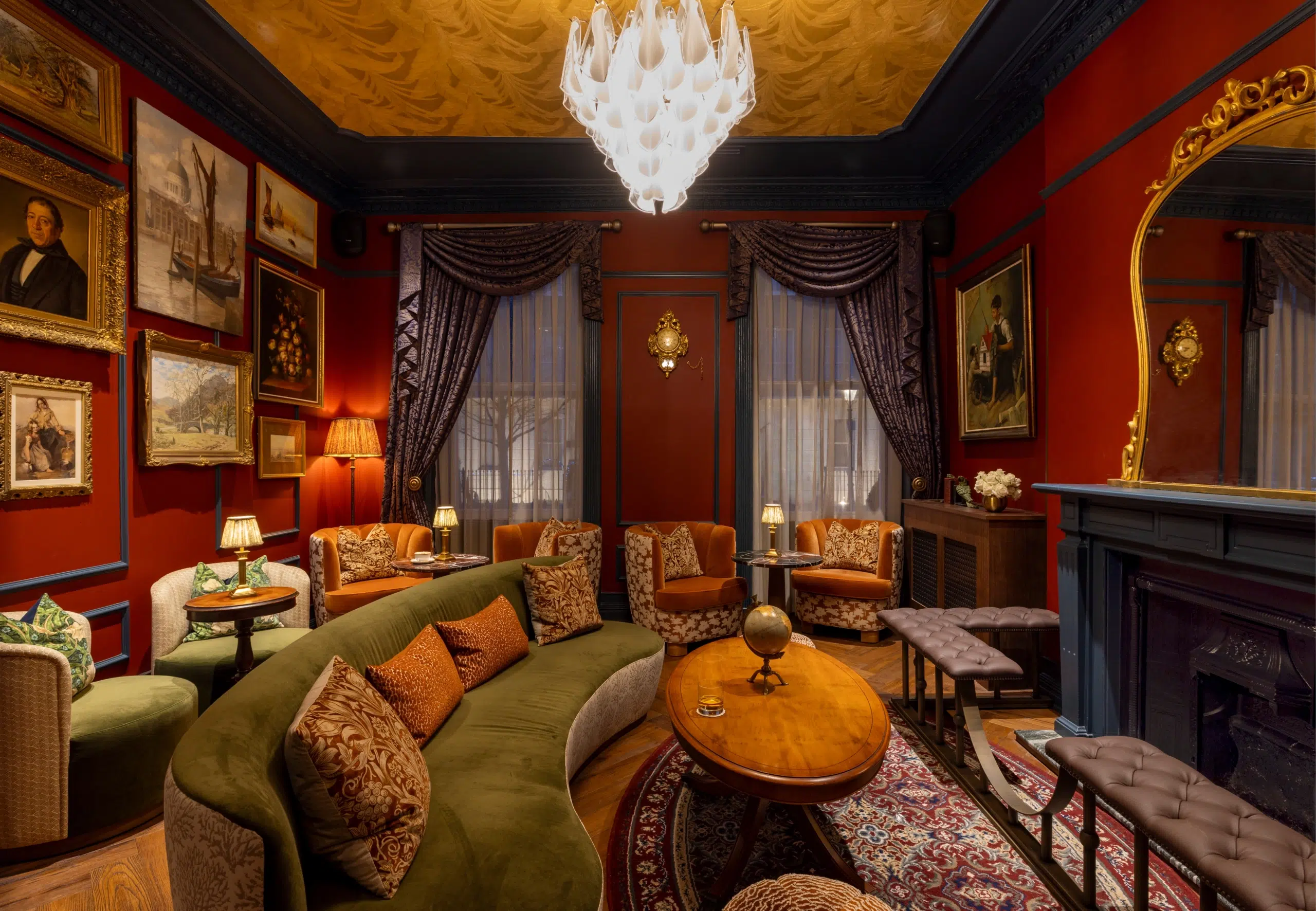 A red living room with velvet chairs and a chandelier