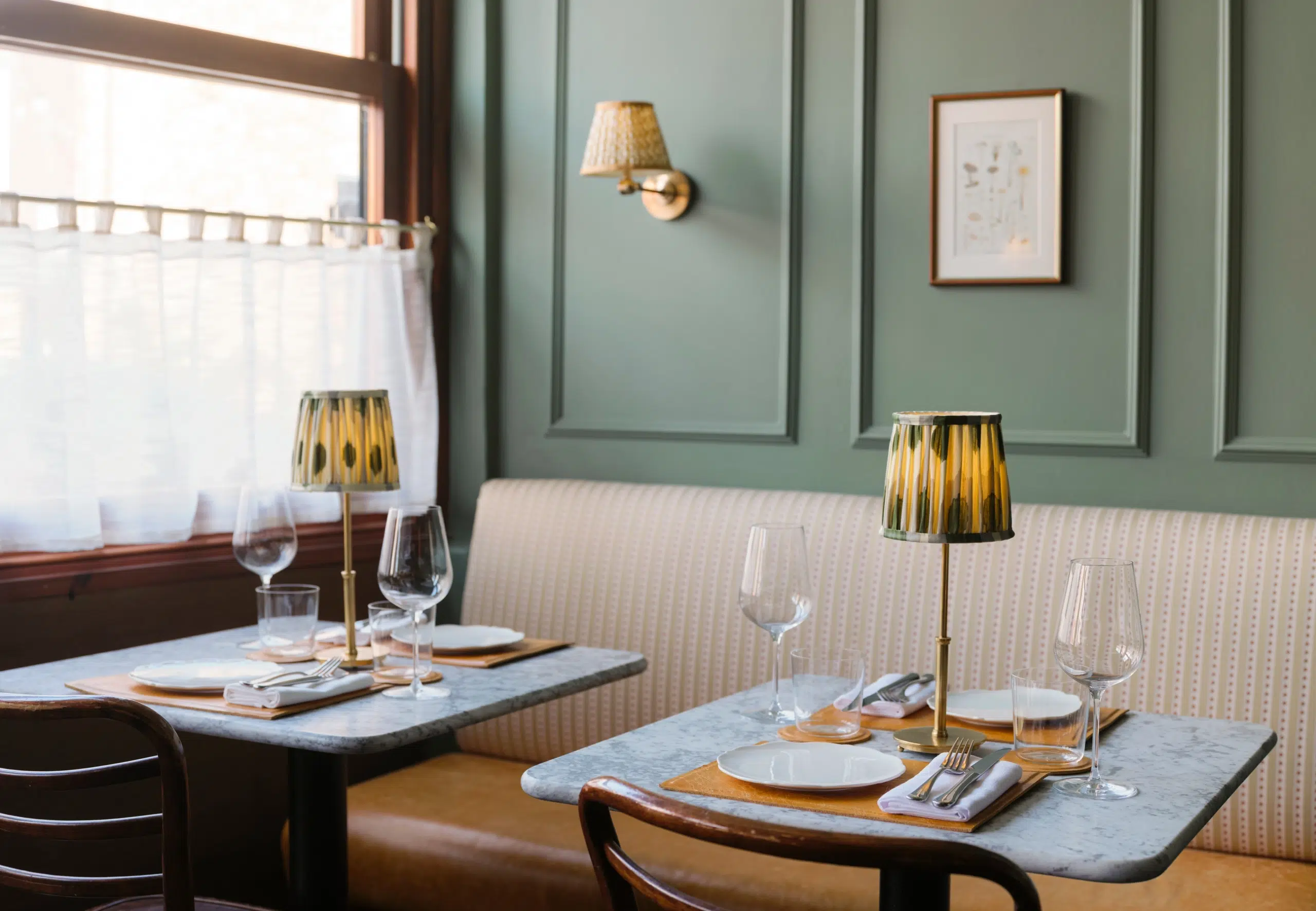 Green panelled dining room with lamps on the table